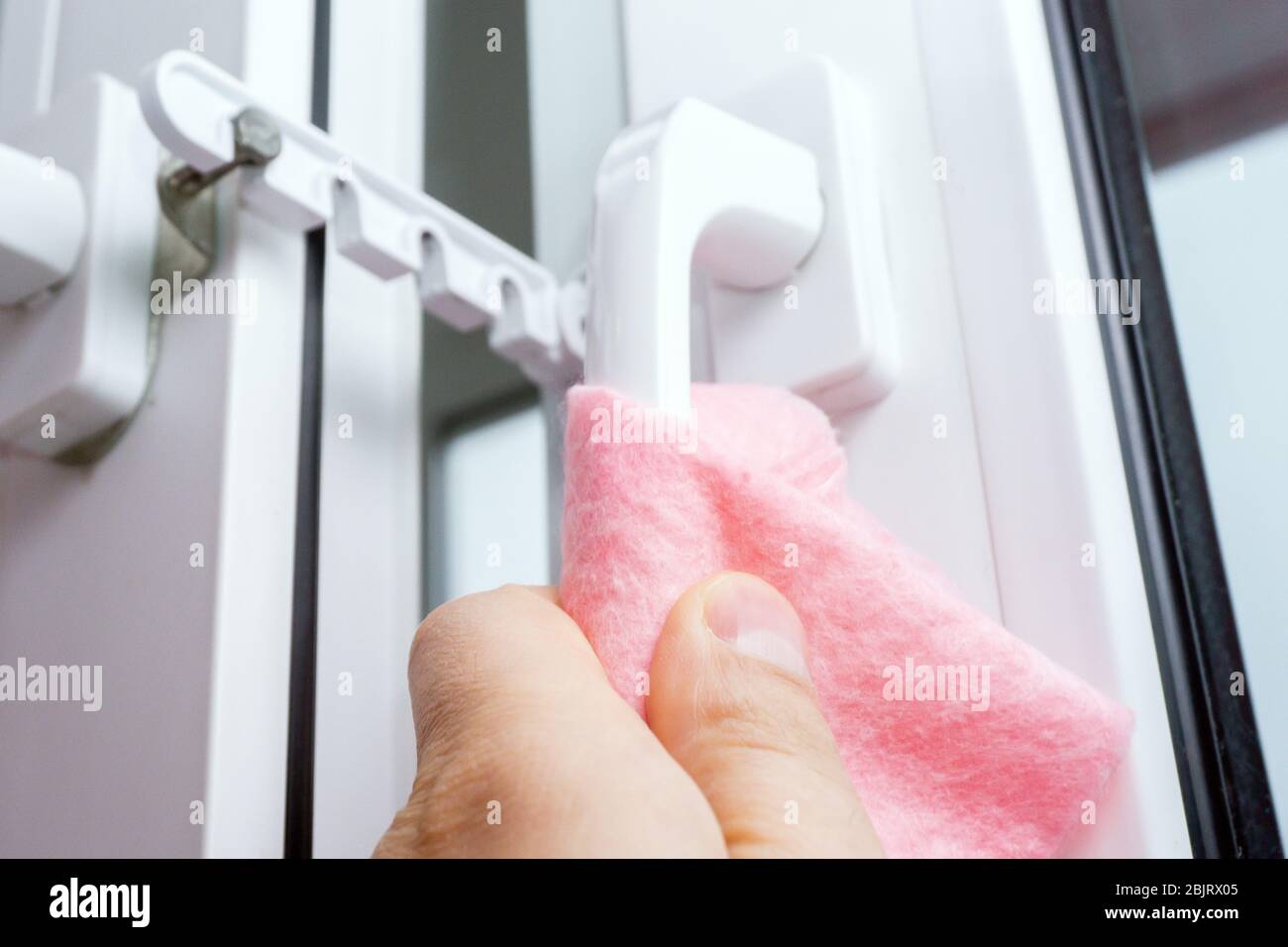 Strofinare la maniglia della porta dal balcone disinfettando l'igiene preventiva. Protegga la sua salute dal coronavirus. Foto Stock