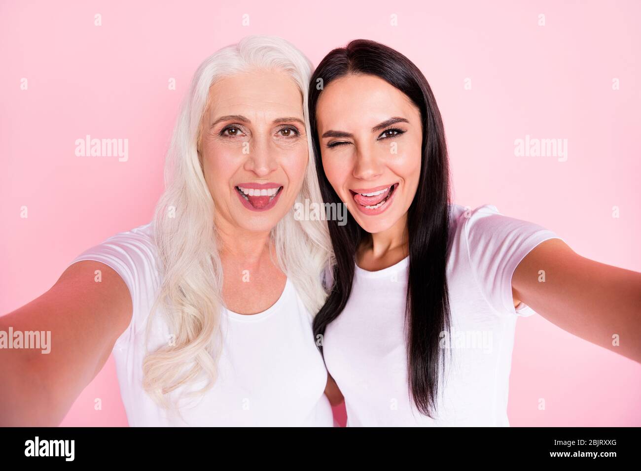 Foto closeup di allegra madre anziana giovane figlia Signore fare selfie migliori amici divertente grimacing espressioni facciali indossare magliette bianche Foto Stock