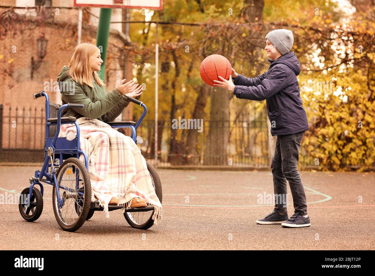 Bambina in sedia a rotelle e ragazzo che gioca con la palla all'aperto Foto  stock - Alamy