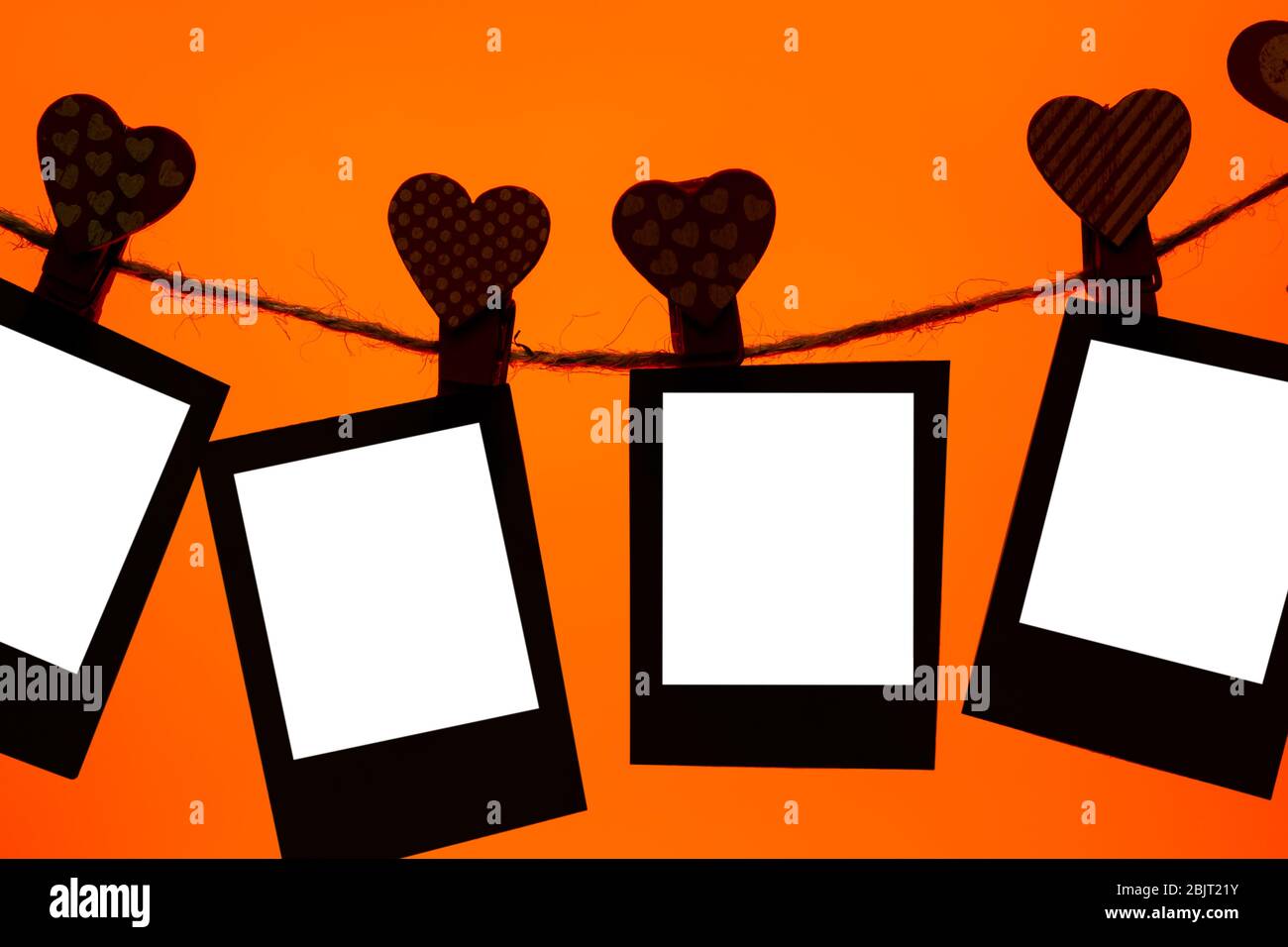 cinque clip di carta di clothespins rossi con un cuore su una corda. San Valentino amore. Lava sfondo lussureggiante. Spazio copia. Mocap Foto Stock