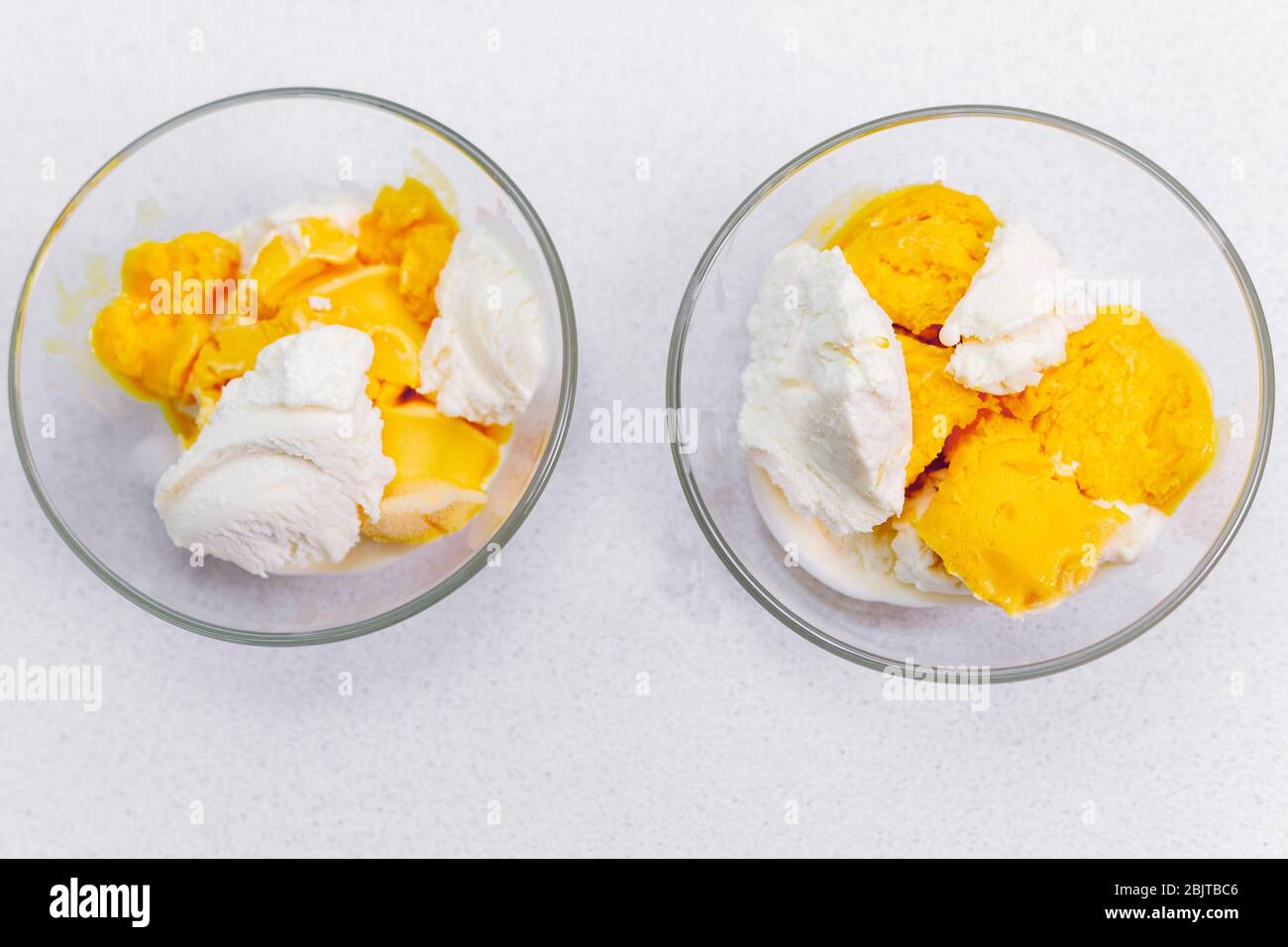 Due gelati alla vaniglia con mango, pesca su fondo chiaro, fuoco selettivo Foto Stock