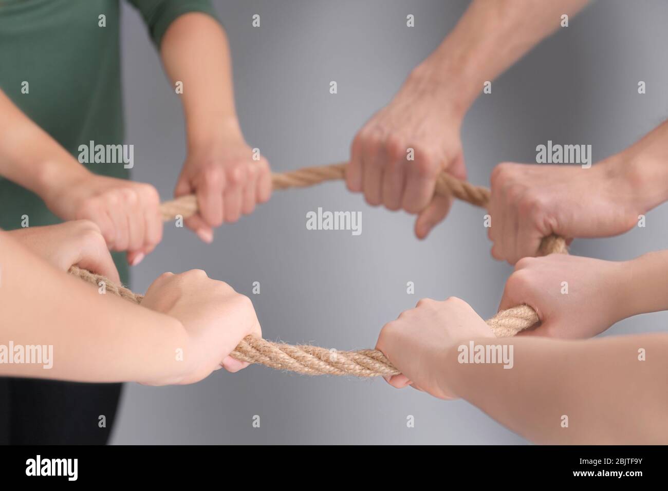 Persone che tengono la corda insieme su sfondo grigio. Concetto di unità Foto Stock