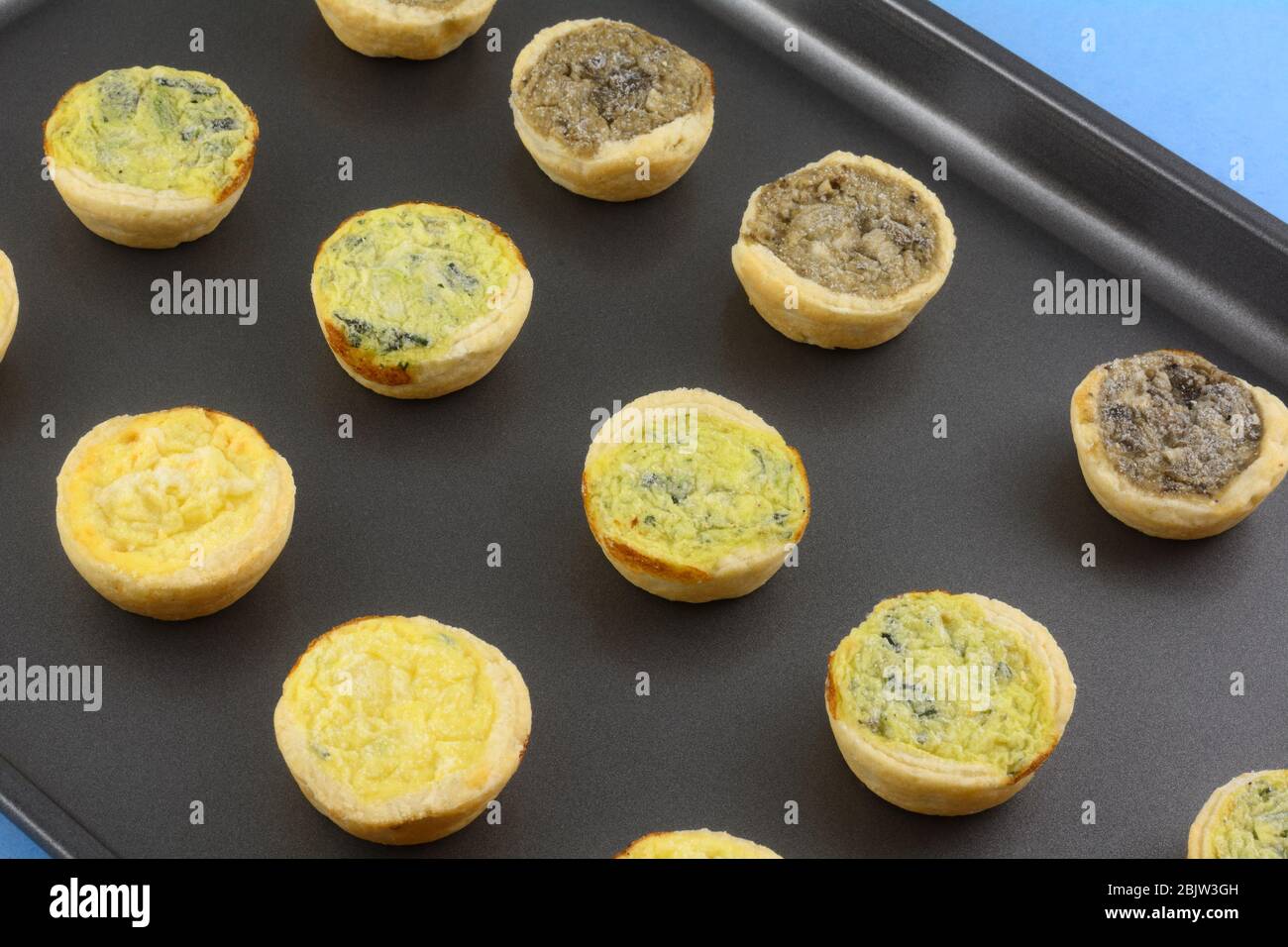 Mini spinaci surgelati di dimensioni ridotte fiorentini, quiche di formaggio e funghi su teglia antiaderente Foto Stock