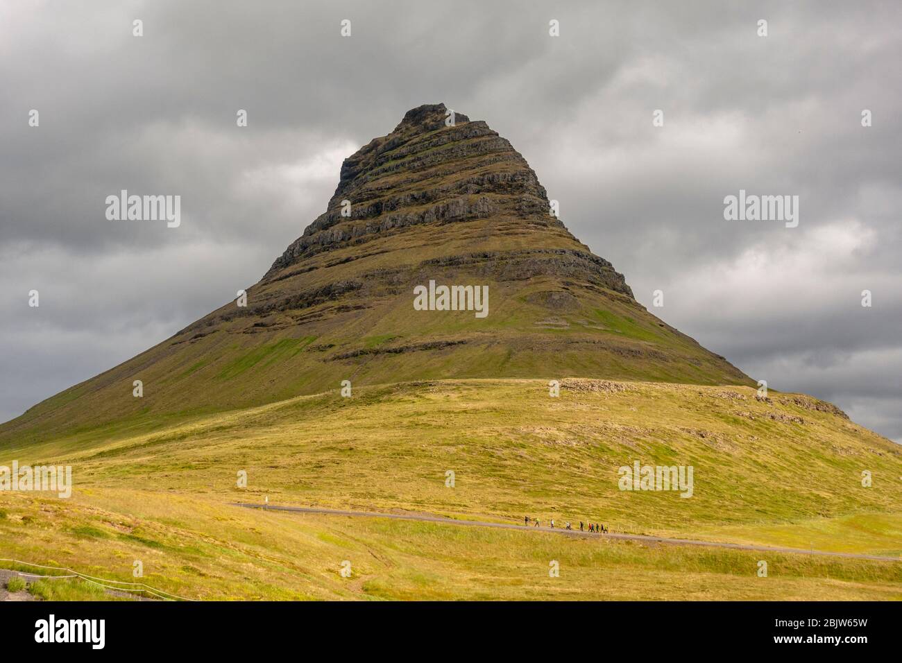 Una piccola linea di camminatori si incrociano davanti al Kirkjufell (la montagna della Chiesa) sulla penisola di Snæfellsnes, Islanda. Foto Stock