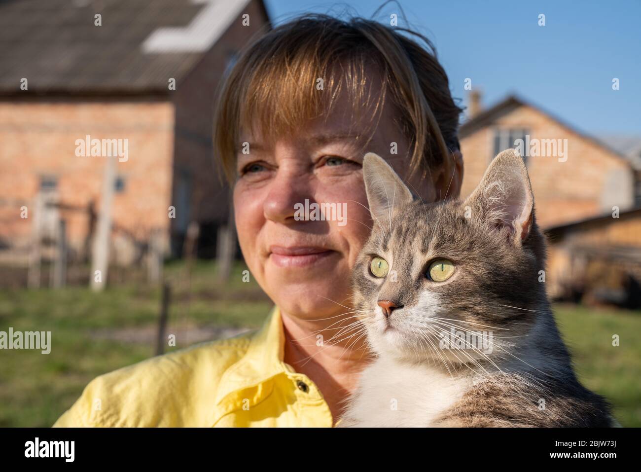 Donna gioca con il suo gatto nel cortile della casa in primavera Foto Stock