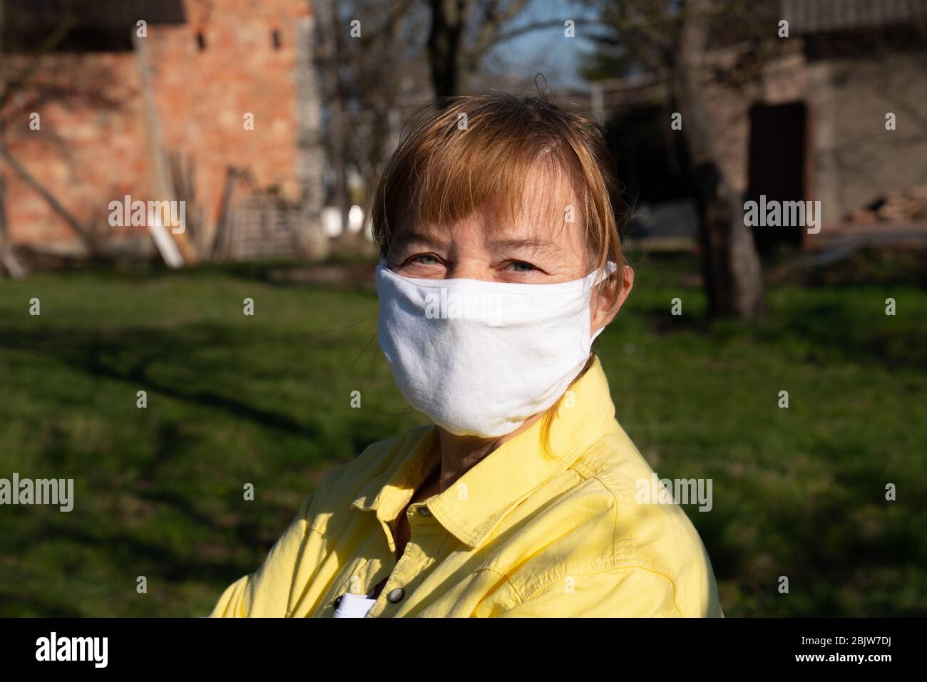 Donna che indossa una maschera facciale, guarda la fotocamera, primo piano Foto Stock