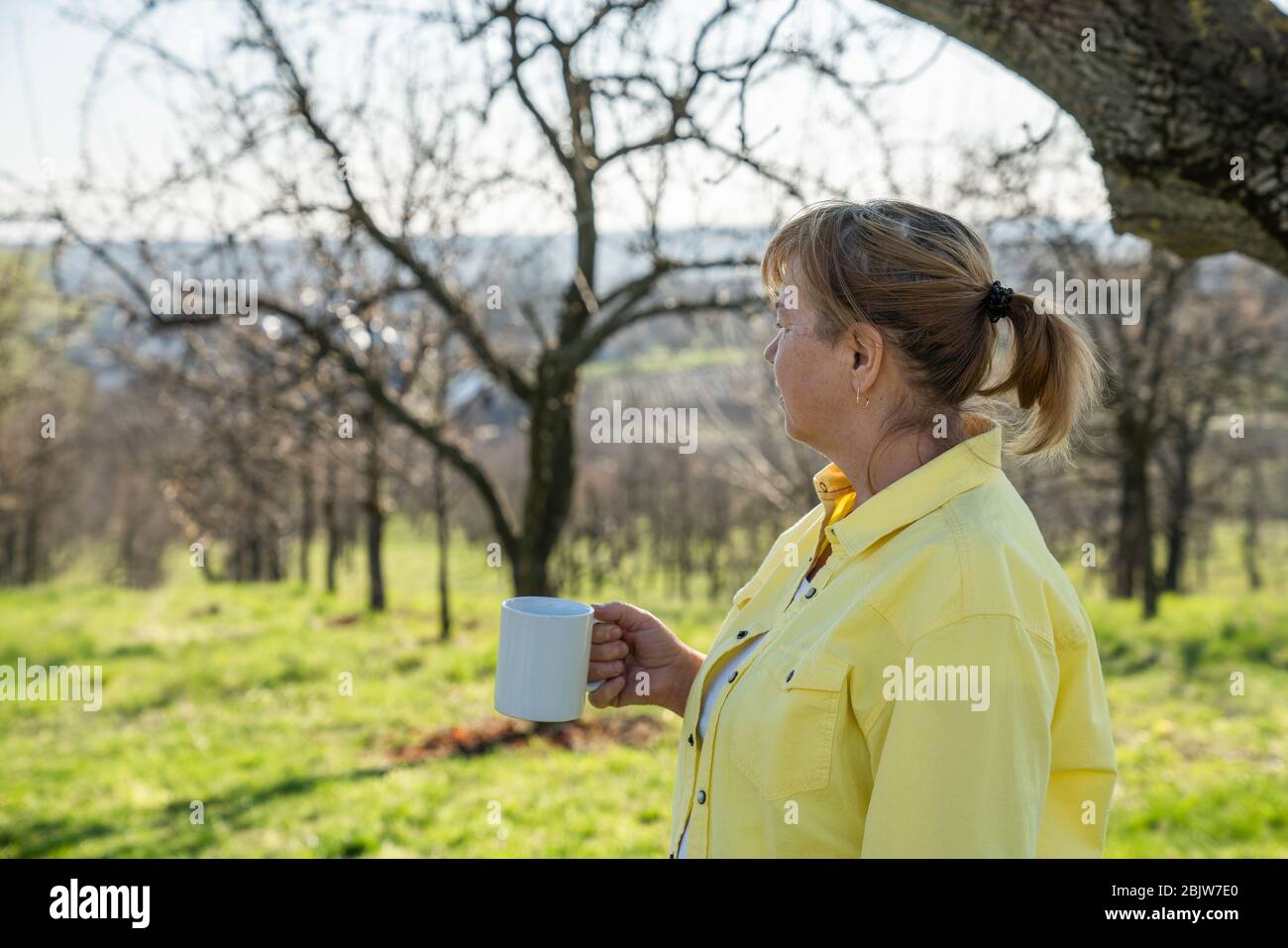 Senior rilassato donna prendendo una pausa con la tazza di tè nel suo giardino Foto Stock