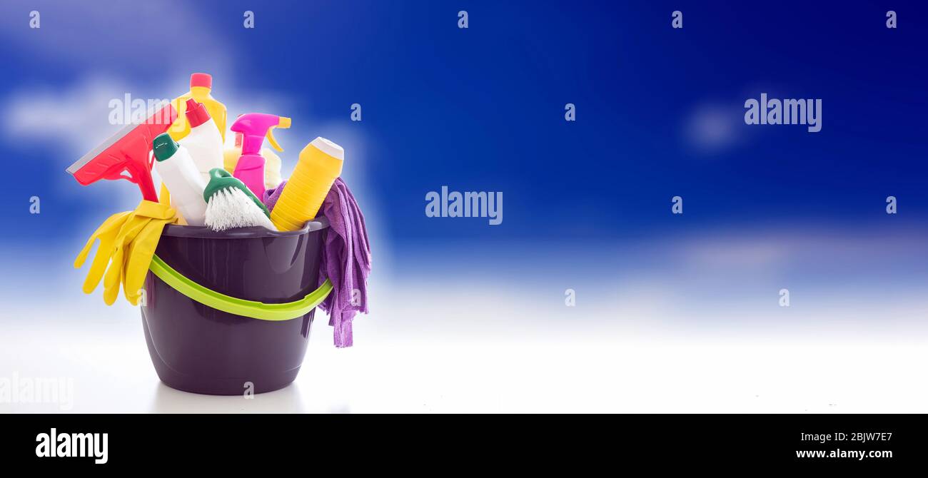Prodotti per la pulizia su sfondo blu. Detergenti chimici in un secchio, concetto di lavaggio finestre, spazio copia, banner Foto Stock
