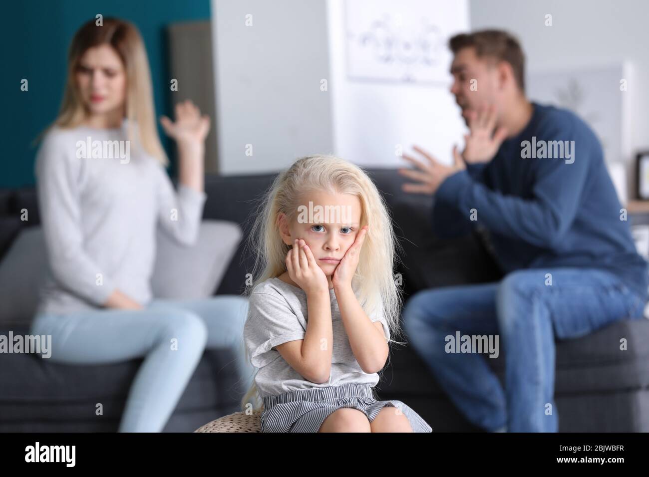 Bambina triste in camera con genitori litiganti. Conflitto familiare Foto Stock
