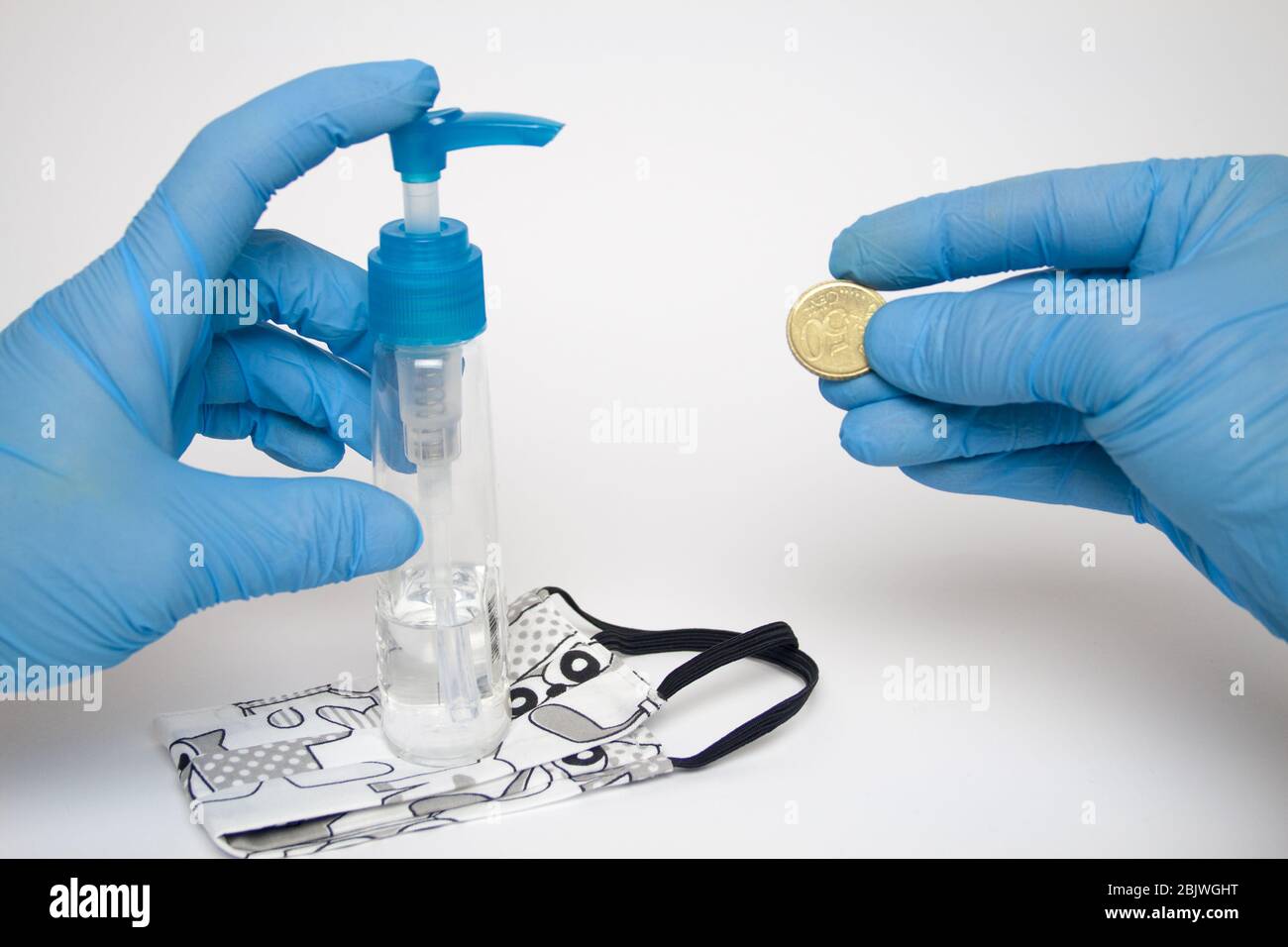 Una mano umana in un guanto protettivo che tiene una moneta accanto ad essa è una maschera disinfettante liquida e protettiva, su uno sfondo bianco. Foto Stock