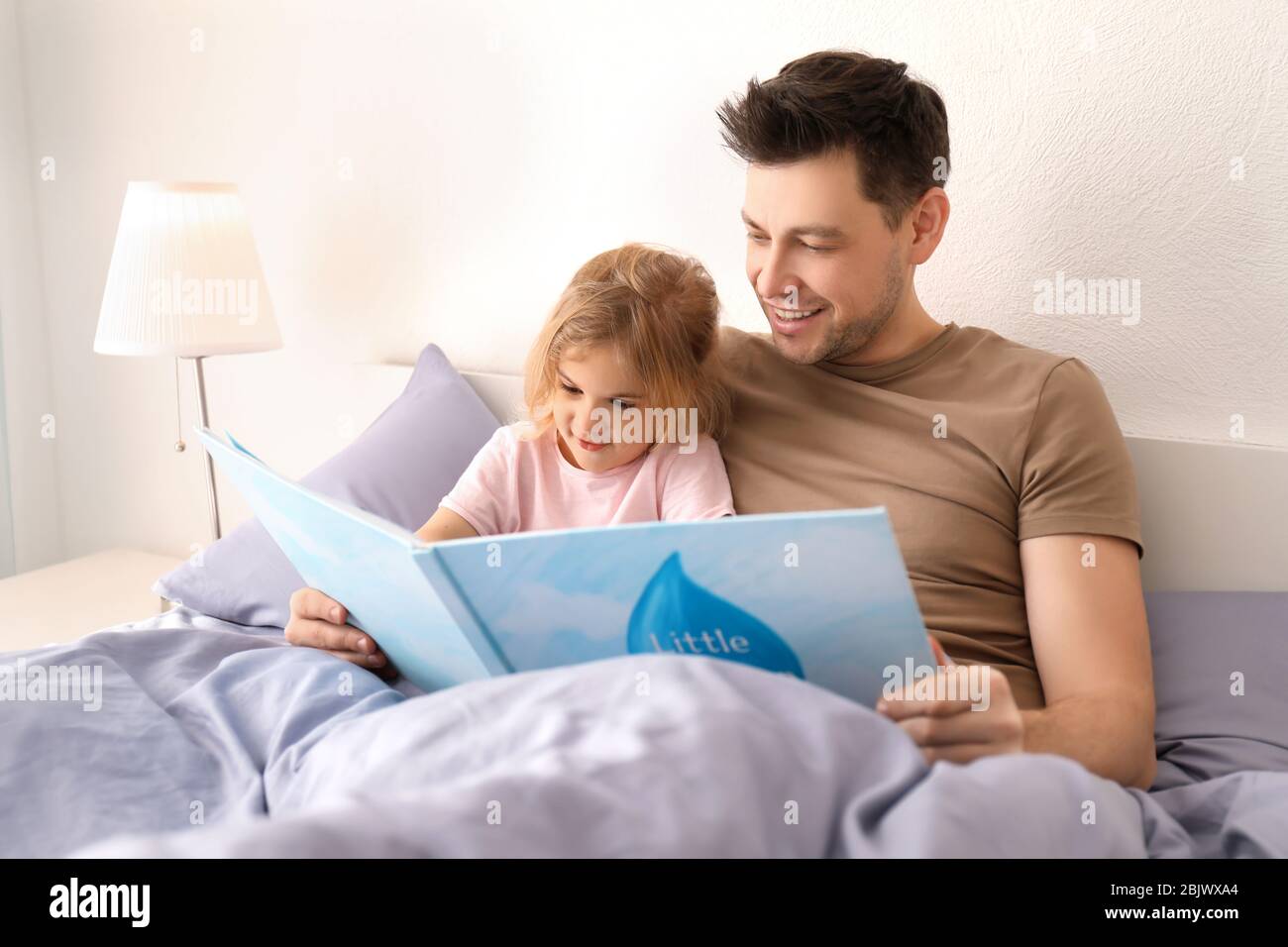 Padre con la figlia piccola che legge la storia di bedtime nel paese Foto Stock