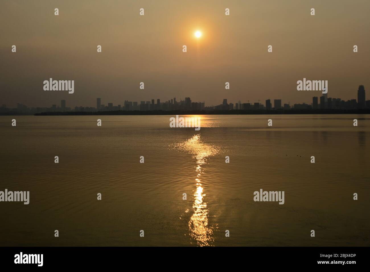 Wuhan: Tramonto sullo skyline della città dal Lago Est, con smog e un cielo nebbia a causa di un inquinamento pesante. Cina Foto Stock