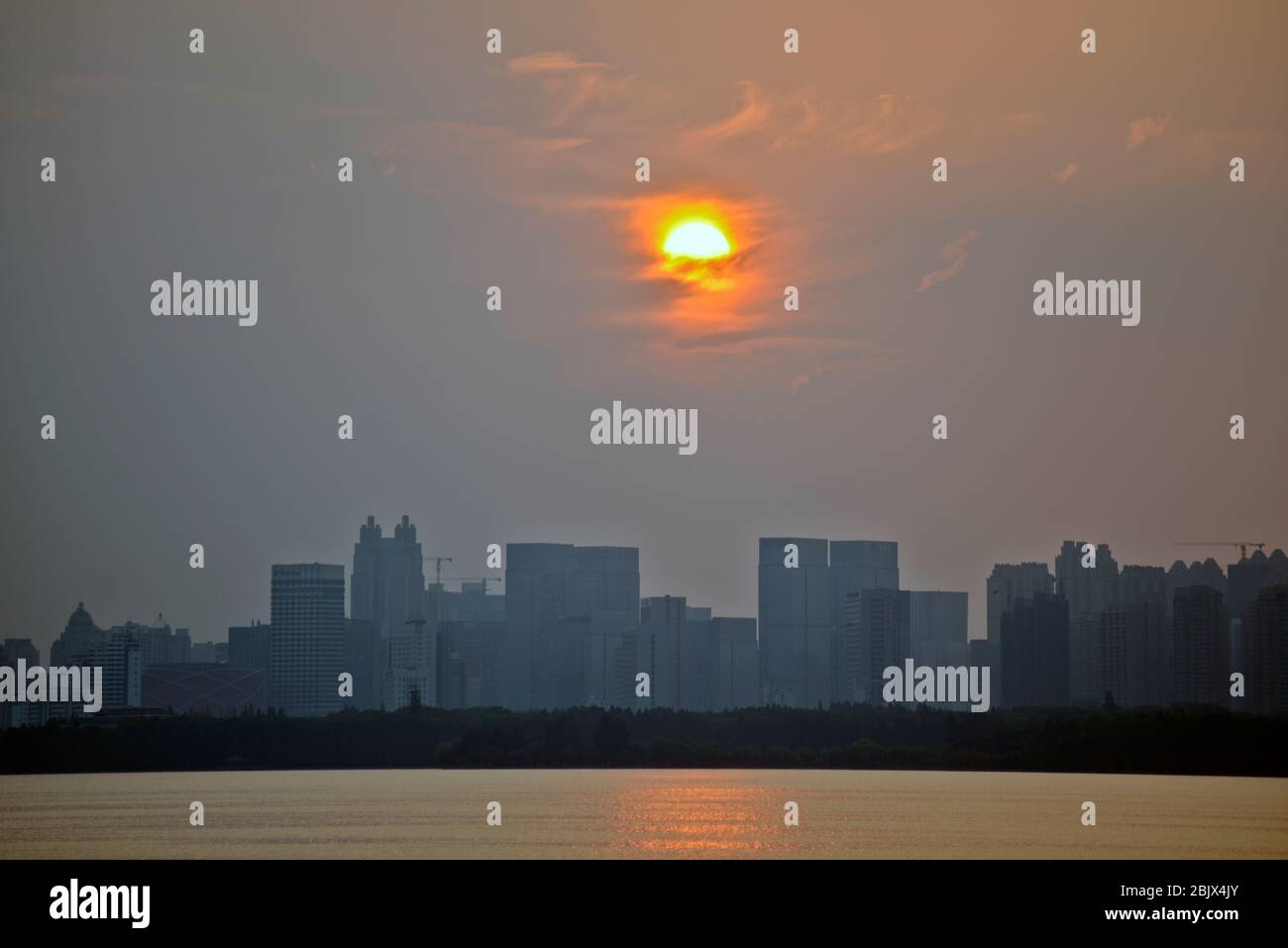 Wuhan: Tramonto sullo skyline della città dal Lago Est, con smog e un cielo nebbia a causa di un inquinamento pesante. Cina Foto Stock
