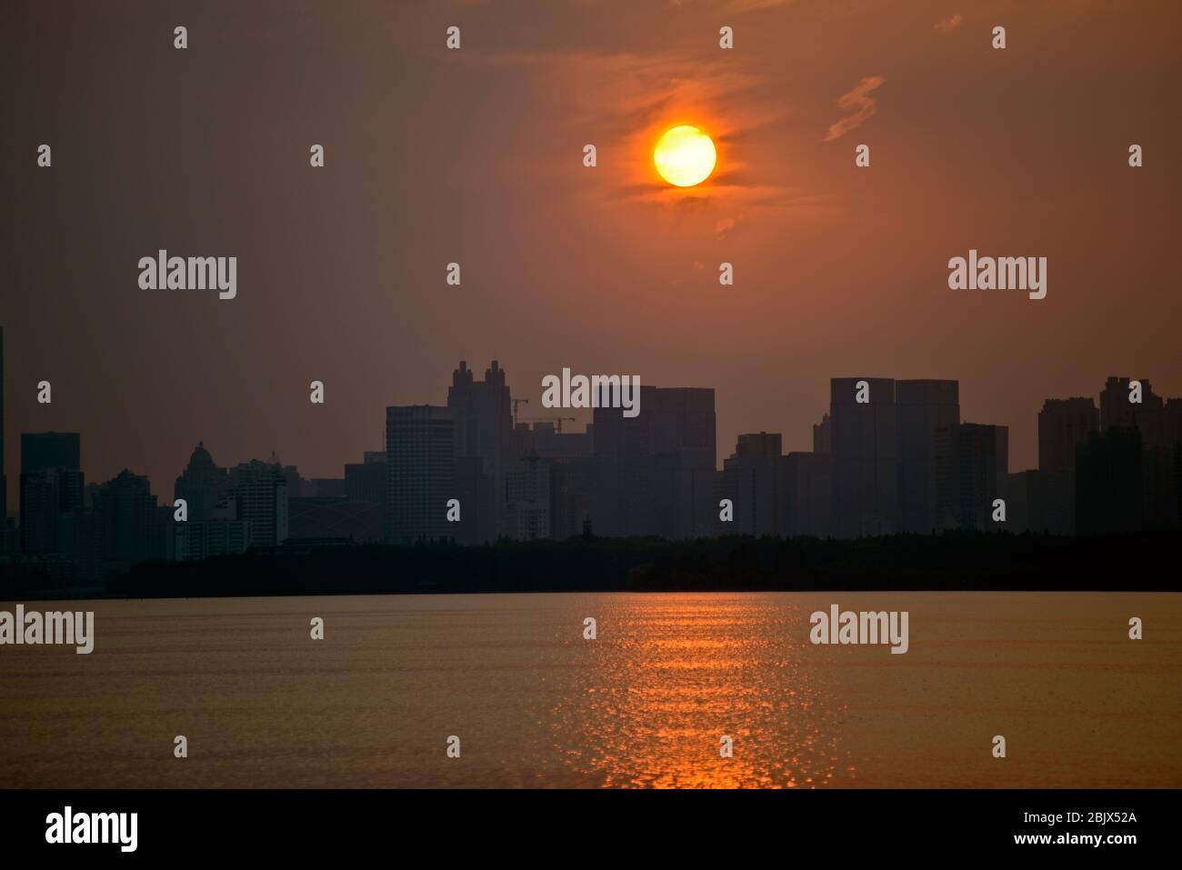 Wuhan: Tramonto sullo skyline della città dal Lago Est, con smog e un cielo nebbia a causa di un inquinamento pesante. Cina Foto Stock