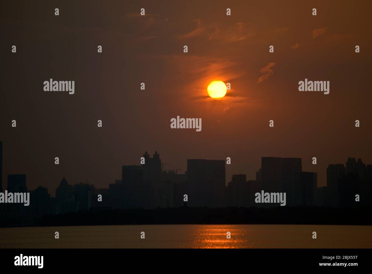 Wuhan: Tramonto sullo skyline della città dal Lago Est, con smog e un cielo nebbia a causa di un inquinamento pesante. Cina Foto Stock