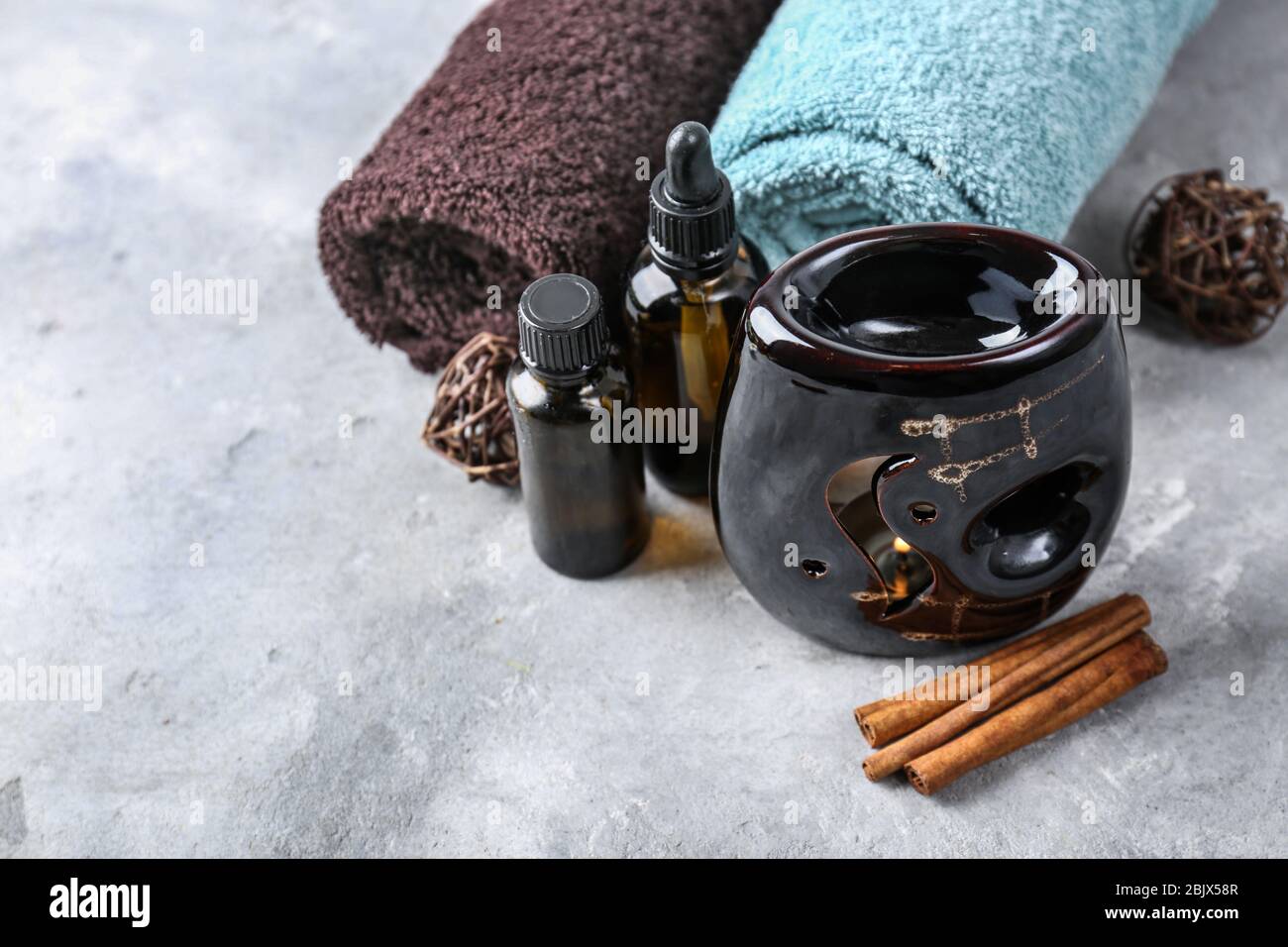 Lampada aromatica, asciugamani e bottiglie di olio sul tavolo Foto Stock