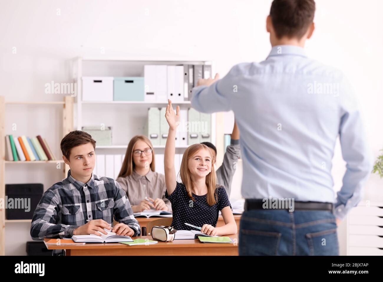 Gruppo di adolescenti che fanno i compiti con l'insegnante in classe Foto Stock