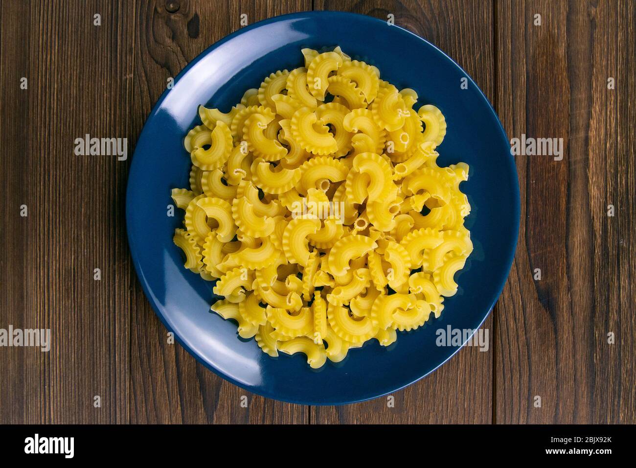Pasta di Pene lisce in piatto blu su fondo di legno scuro. Viste superiori  Foto stock - Alamy