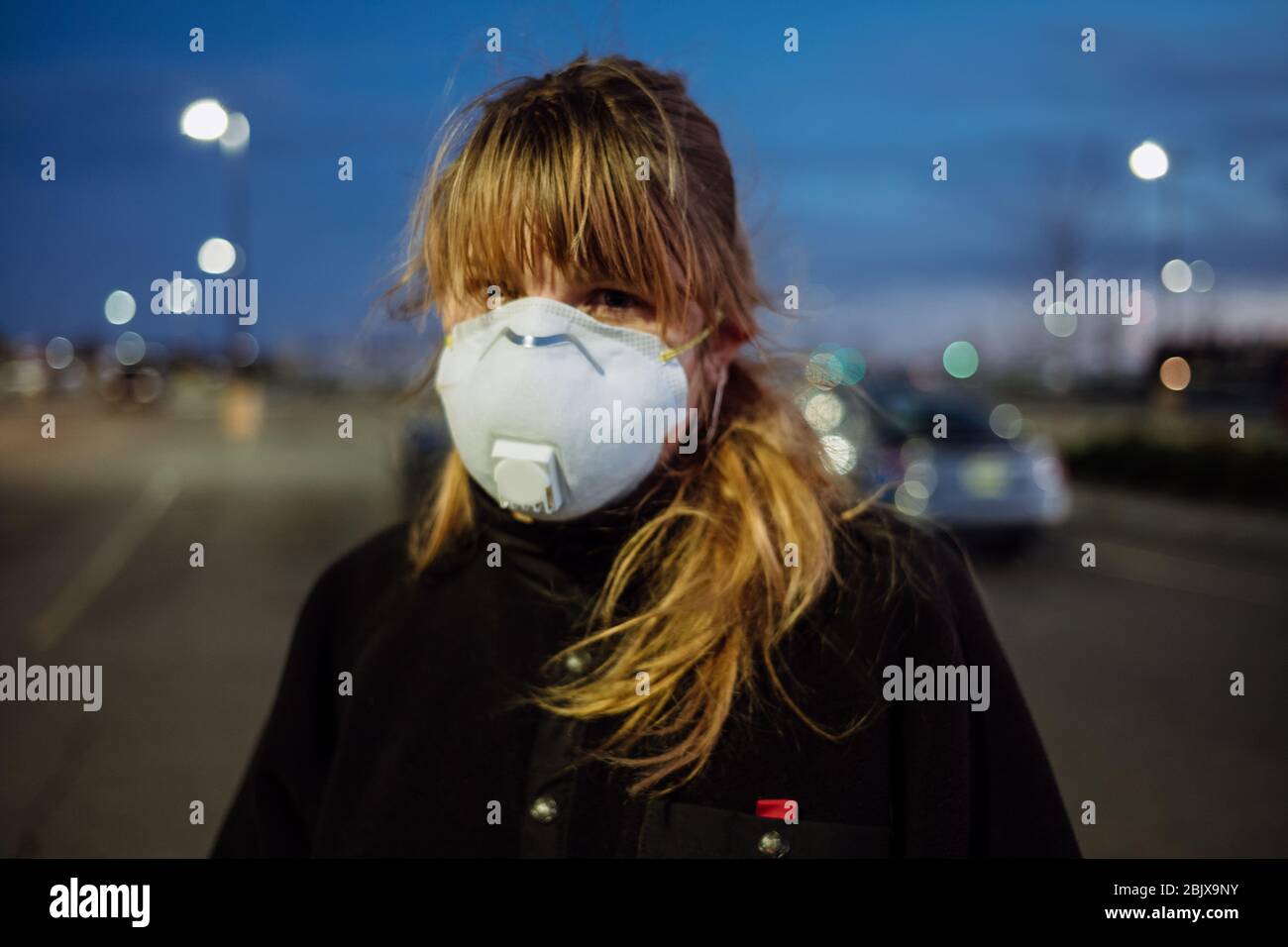 Una donna che indossa una maschera facciale PPE e guanti al di fuori di un negozio di alimentari durante la pandemia globale Covid-19. Foto Stock