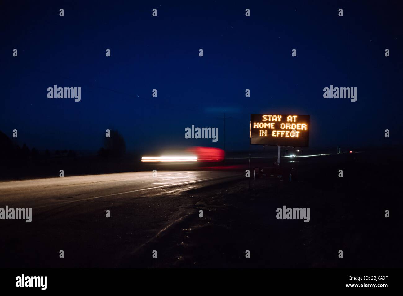 L'ordine di soggiorno a casa è visibile sul cartello digitale della strada di notte mentre le auto passano. Covid-19 pandemico, soggiorno a casa ordine Foto Stock