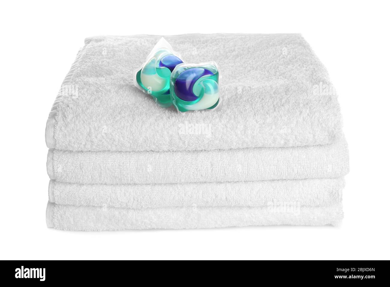 Pile di asciugamani piegati puliti e di cialde detergenti su sfondo bianco. Giorno di lavanderia Foto Stock