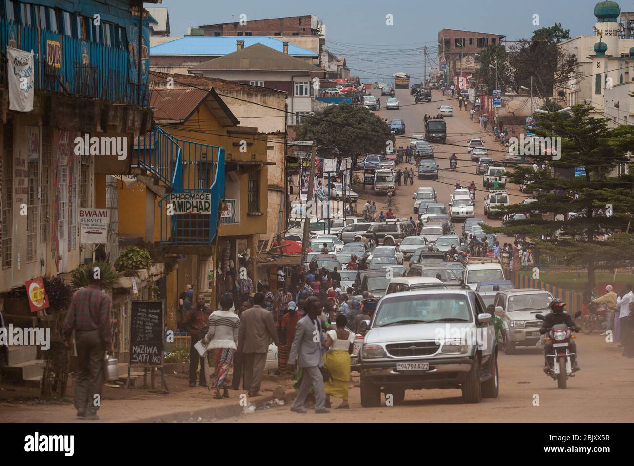 Bukavu, Repubblica Democratica del Congo : traffico sulla strada polverosa centrale della città. Automobili e motociclette Foto Stock