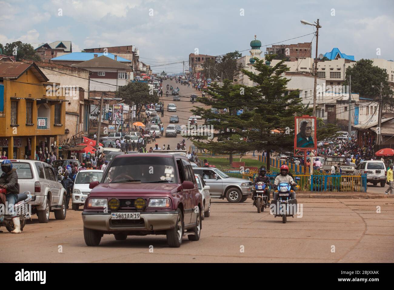 Bukavu, Repubblica Democratica del Congo : traffico sulla strada polverosa centrale della città. Automobili e motociclette Foto Stock