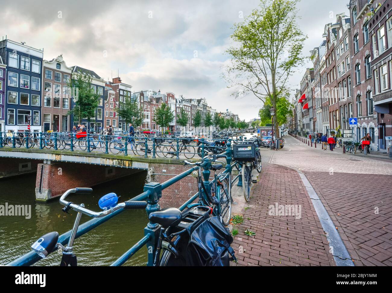 Le biciclette si parcheggiano lungo il canale e su un ponte in un'intensa giornata autunnale ad Amsterdam nei Paesi Bassi Foto Stock