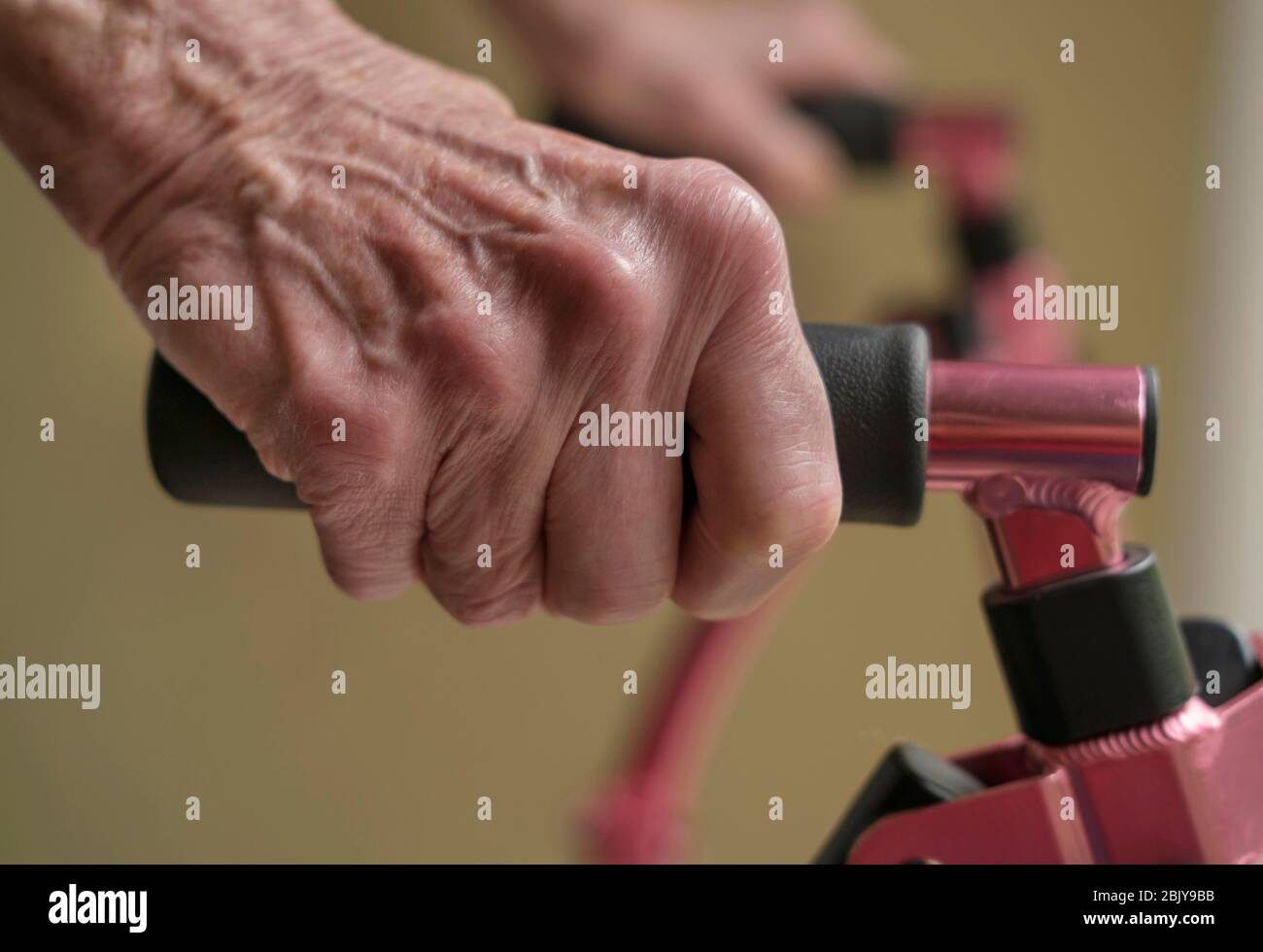 Primo piano delle mani di una donna anziana su un camminatore di mobilità Foto Stock