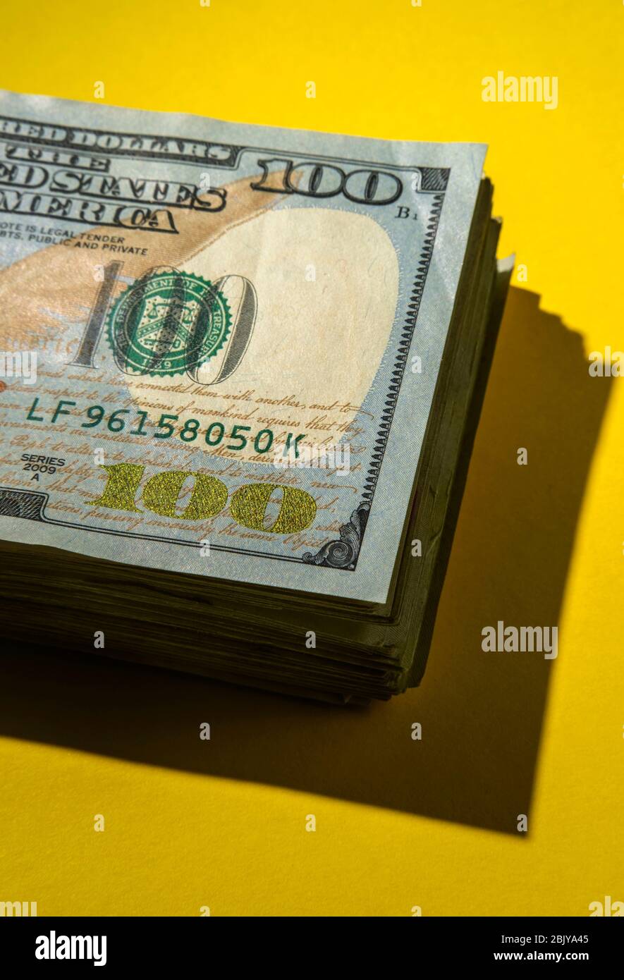 Pila di 100 dollari di bollette sulla backgroundÂ gialla Foto Stock