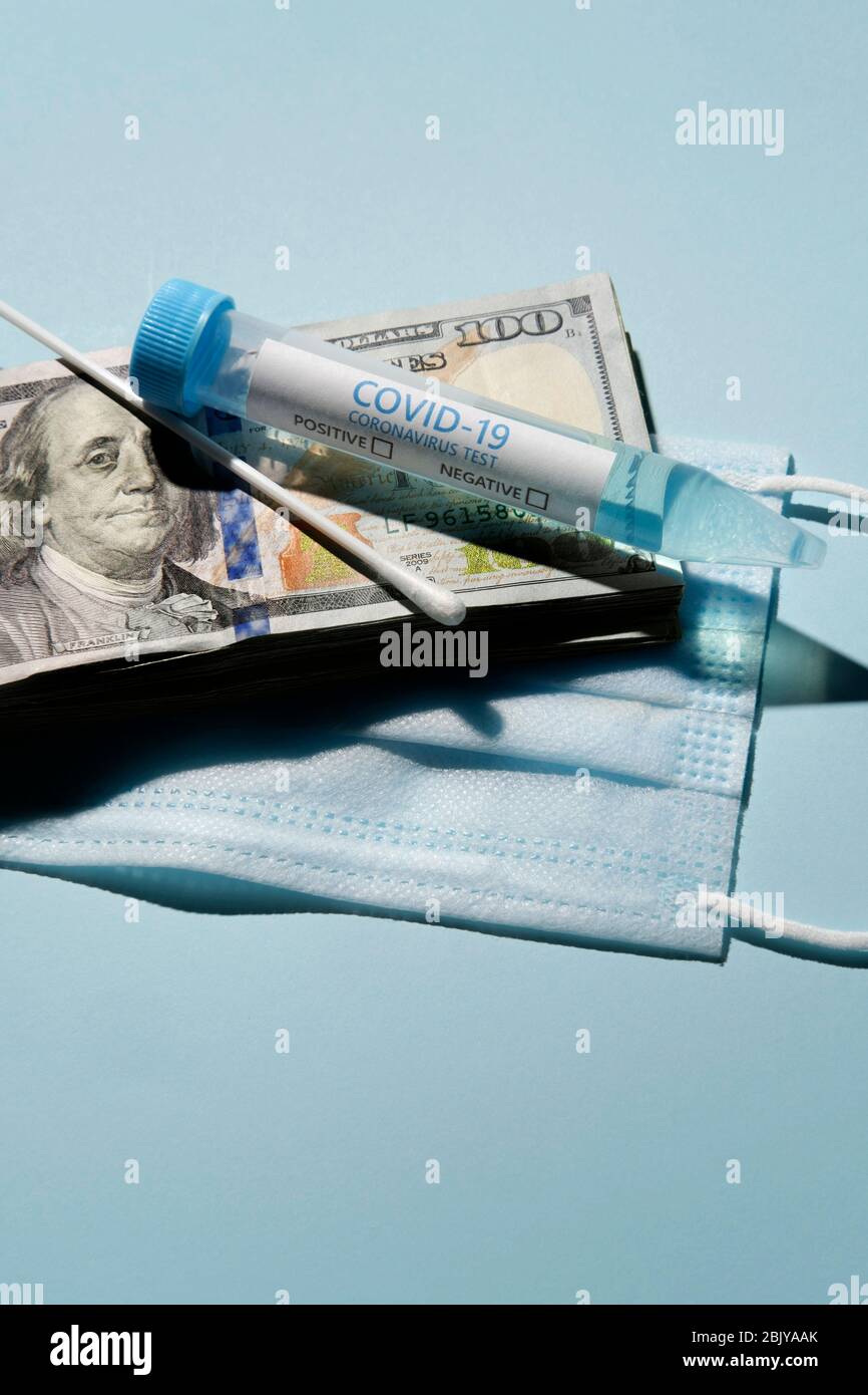 Fiala per analisi Covid-19 e tampone su una pila di 100 dollari bollette e maschera medica Foto Stock