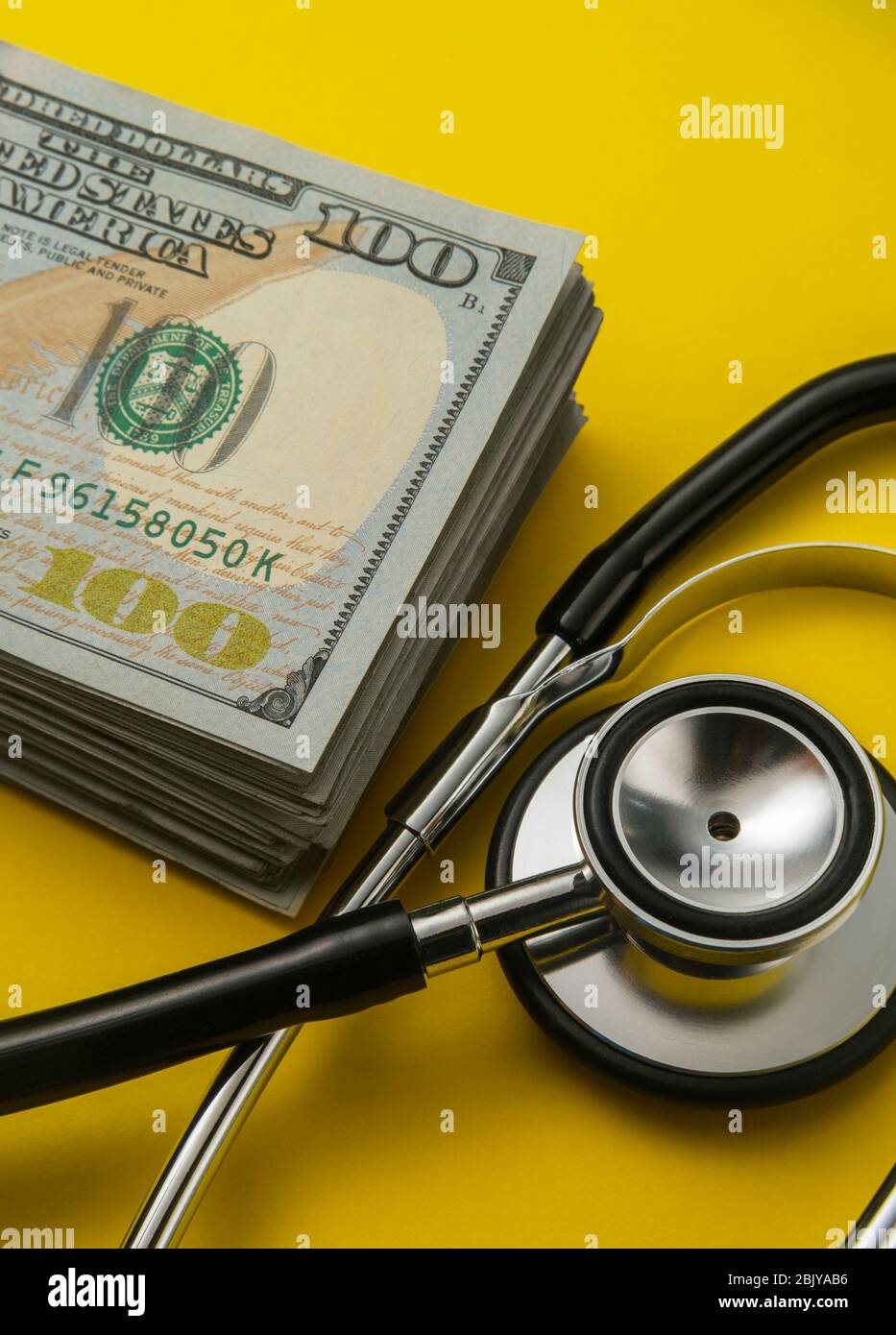 Pila di 100 dollari di bollette e stethoscopeÂ sul giallo backgroundÂ Foto Stock