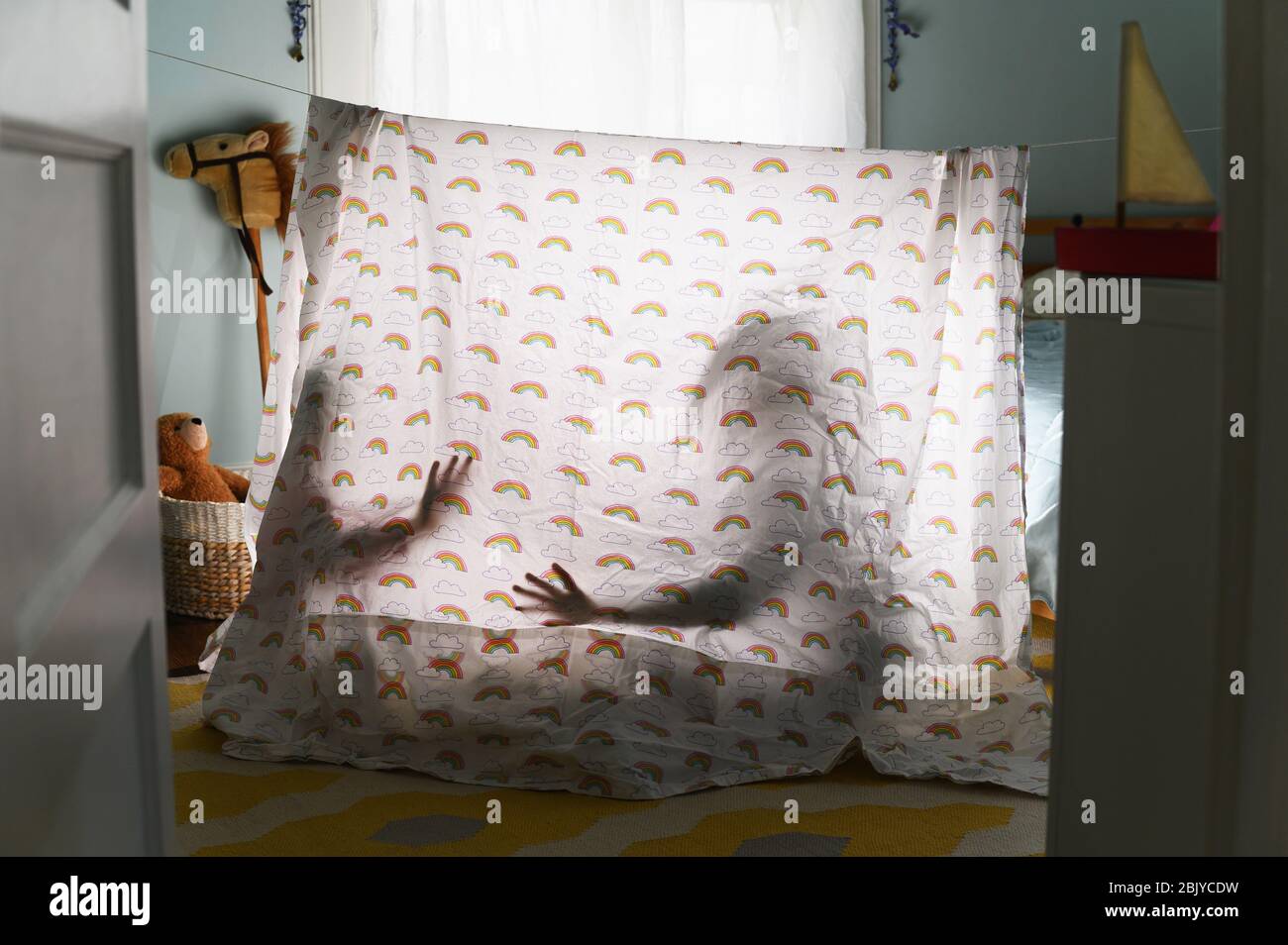 Ombre di bambini dietro tenda da letto in asilo nido Foto Stock