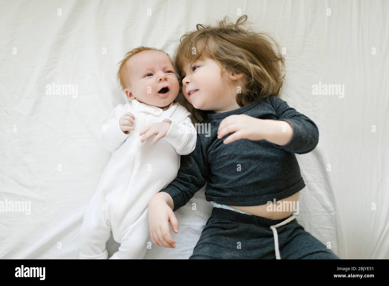 Fratelli (2-5 mesi, 2-3) sdraiati sul letto Foto Stock