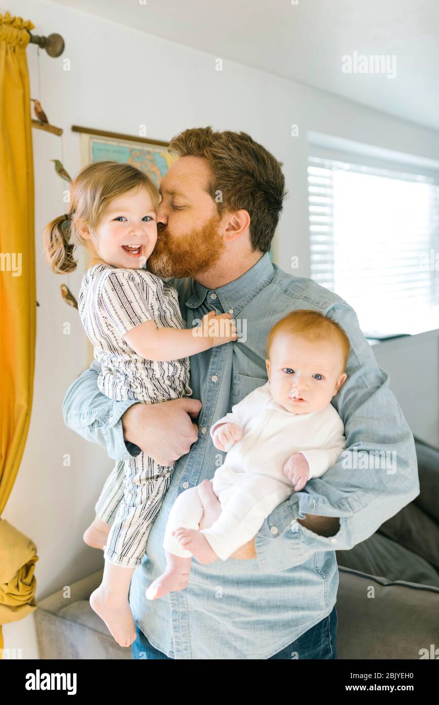 Padre che tiene e bacia i bambini (2-3 mesi, 2-3) Foto Stock