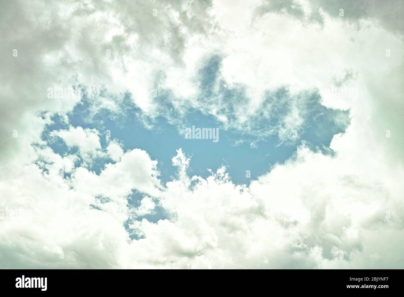 Un'apertura di cielo blu attraverso le nubi spesse Foto Stock