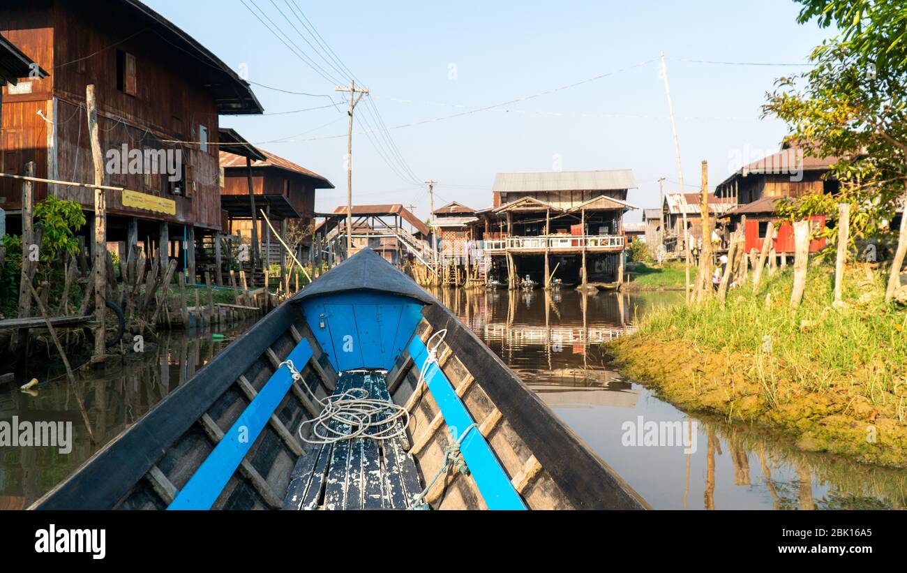 Nyaungshwe, Myanmar : 12 marzo 2020 - giro in barca a coda lunga sul canale del lago Inle in un piccolo villaggio rurale con case su palafitte in acqua Foto Stock