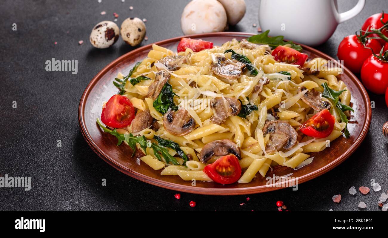 Pasta con funghi, formaggio, spinaci, rukkola e pomodori ciliegini. Piatti italiani, cultura mediterranea Foto Stock