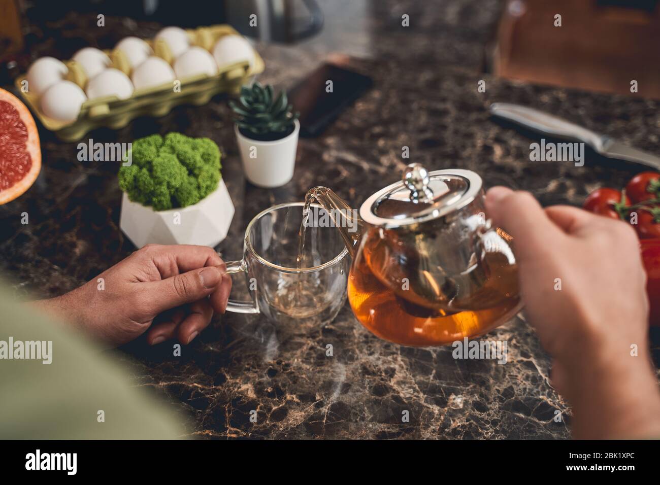 Uomo che riempie una tazza con tè nero Foto Stock