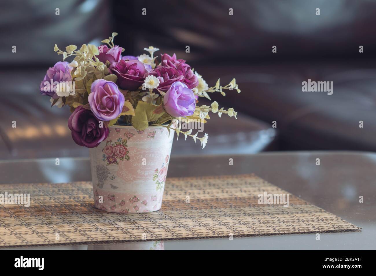 Piante artificiali e rose in pentola con sfondo sfocato Foto Stock