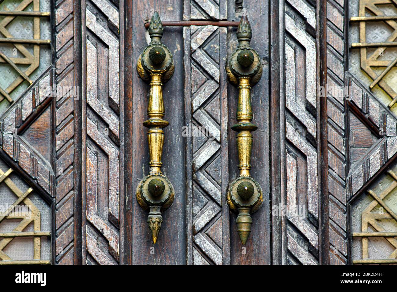 Porta d'ingresso vintage in legno con grandi maniglie intagliate. Foto Stock