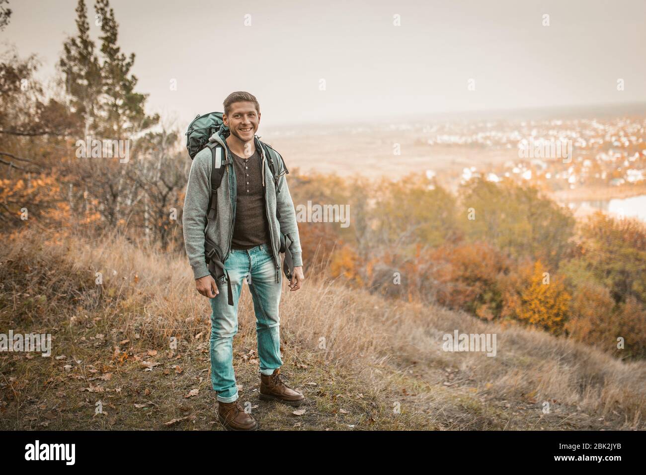 Allegro turista con zaino in piedi su Hillside Foto Stock