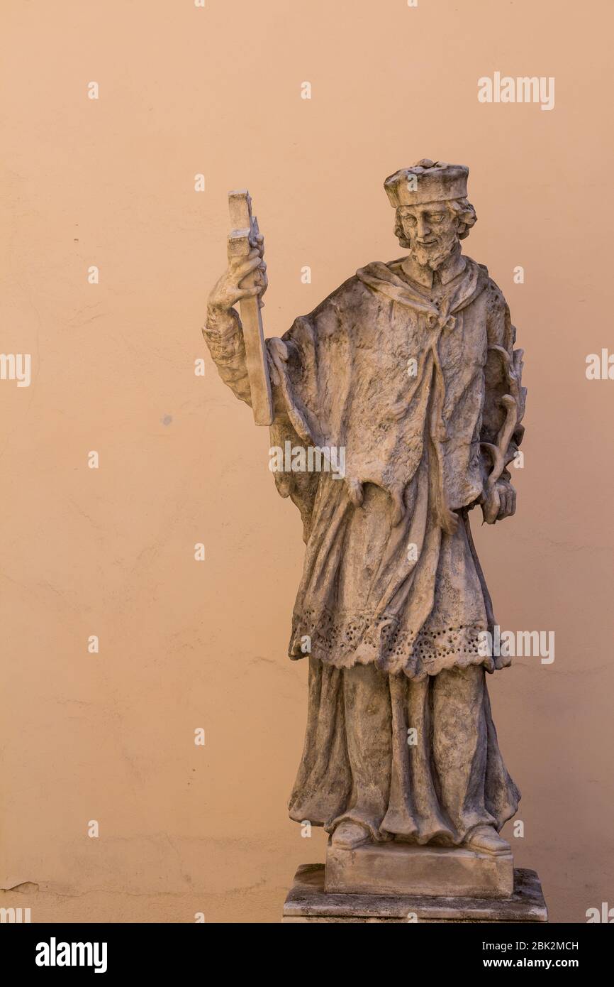 Statua al cortile della canonica di San Martino. San Jan Nepomucky, tono in tono con il muro sullo sfondo. Bratislava, Slovacchia. Foto Stock