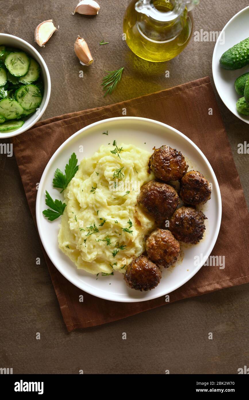 Carni macinate cotolette con purè di patate su piastra bianca su sfondo marrone. Vista superiore, laici piatta Foto Stock