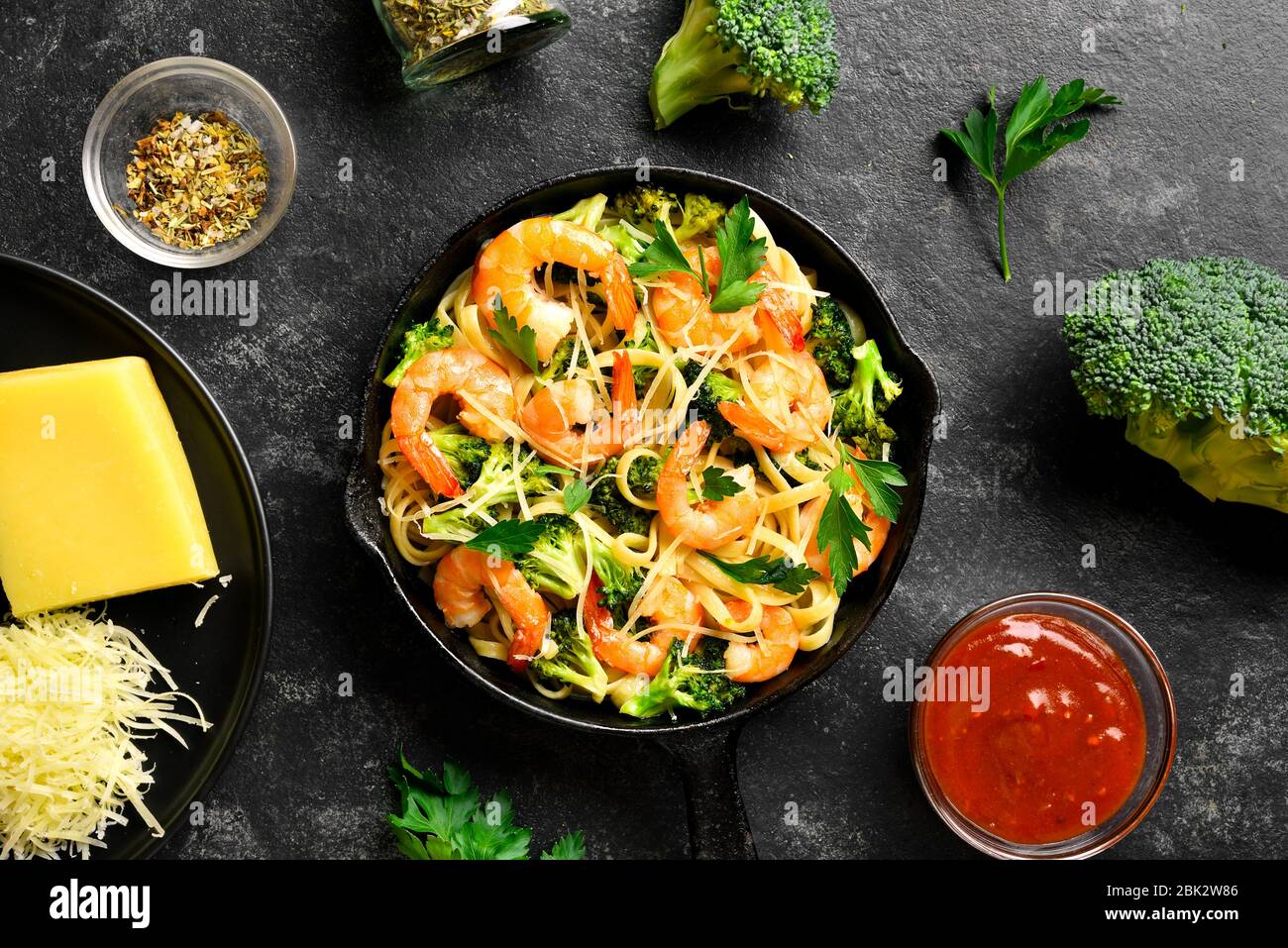 Gamberi e broccoli su fondo di pietra scura. Gustoso piatto sano per cena. Vista dall'alto, disposizione piatta Foto Stock