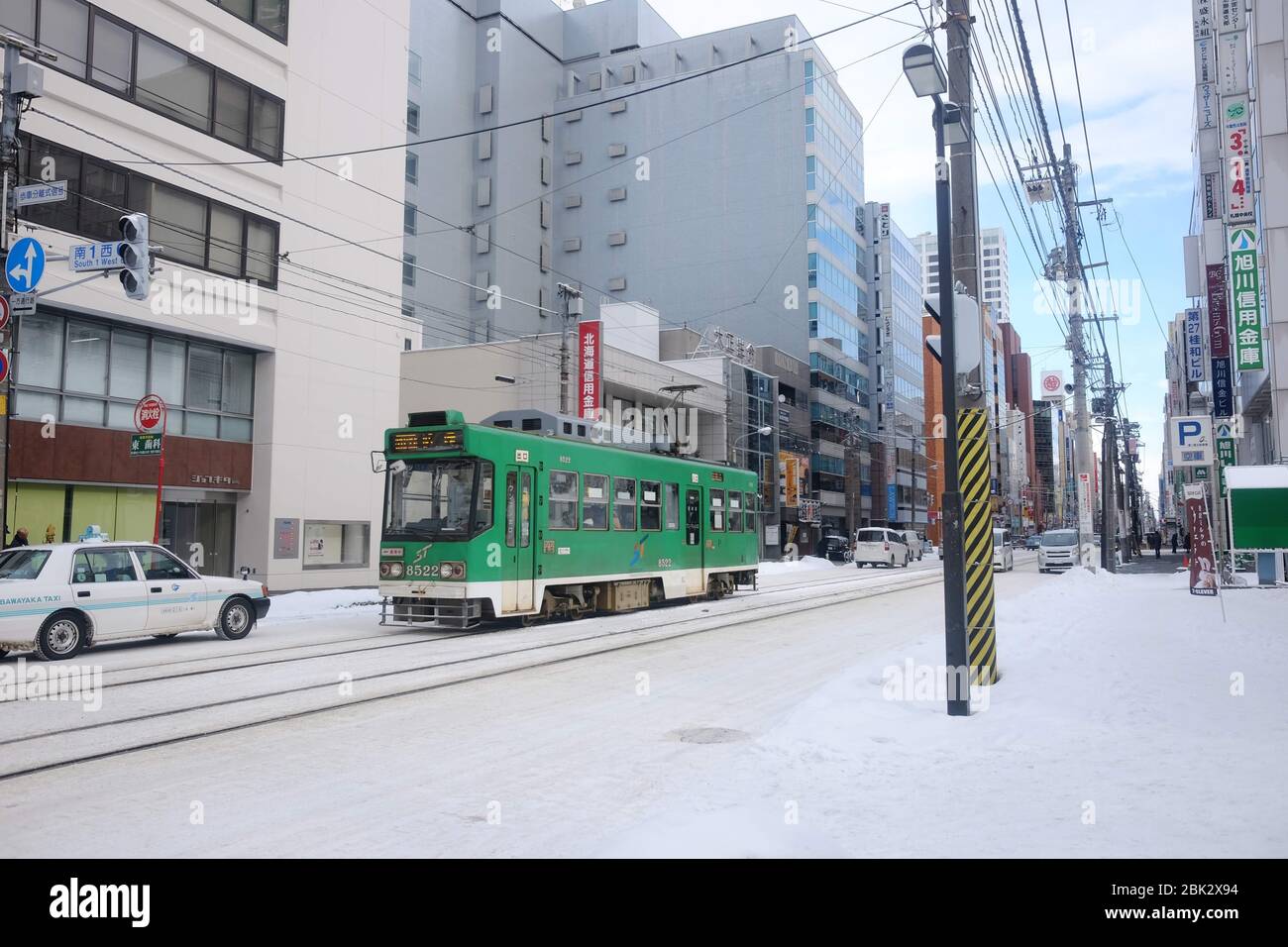Un tram verde della città di Sapporo tra gli edifici, Hokkaido, Giappone Foto Stock