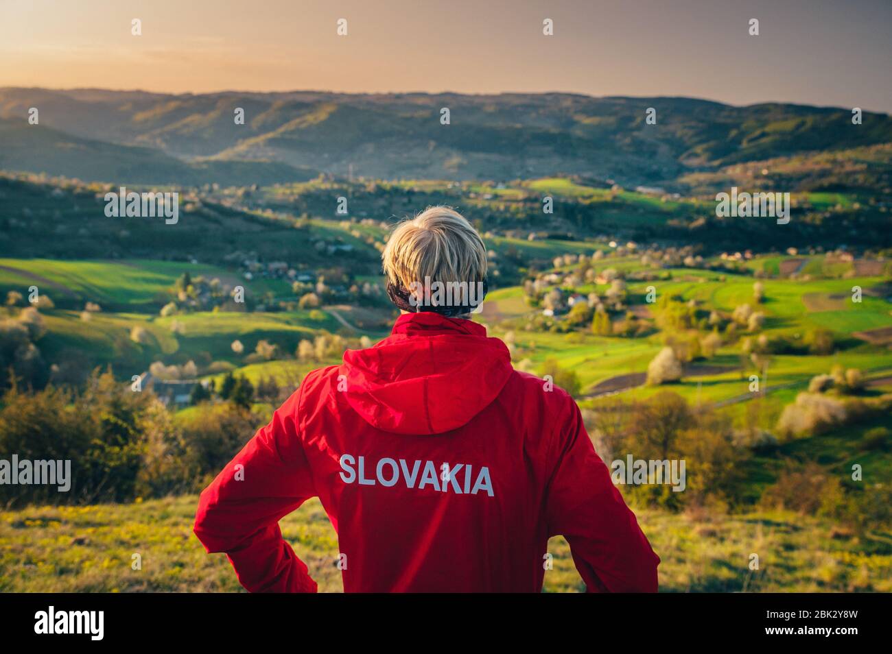 Slovacchia scritta su una giacca rossa di runner maschile che guarda il bellissimo paesaggio mattutino primaverile Foto Stock