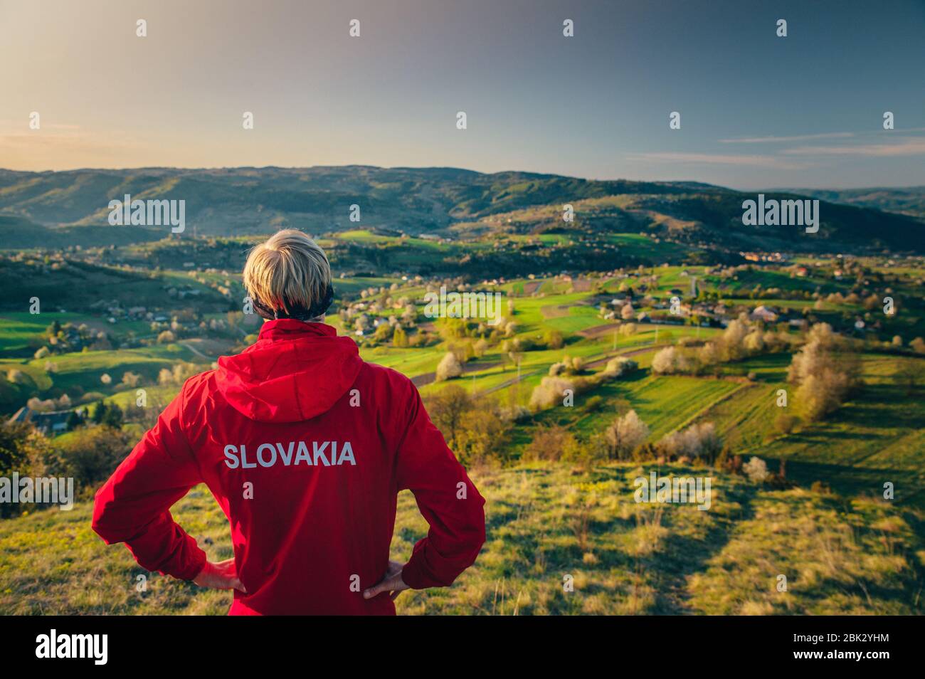 Corridore slovacco in piedi sulla cima della collina e guardando il colorato paesaggio primaverile mattina Foto Stock