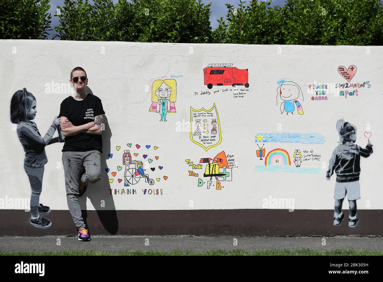 L'artista irlandese emmalene Blake con il suo ultimo murale a tema coronavirus, creato con l'aiuto di bambini locali, a Kingswood, Dublino, che rende omaggio ai lavoratori in prima linea. Foto Stock