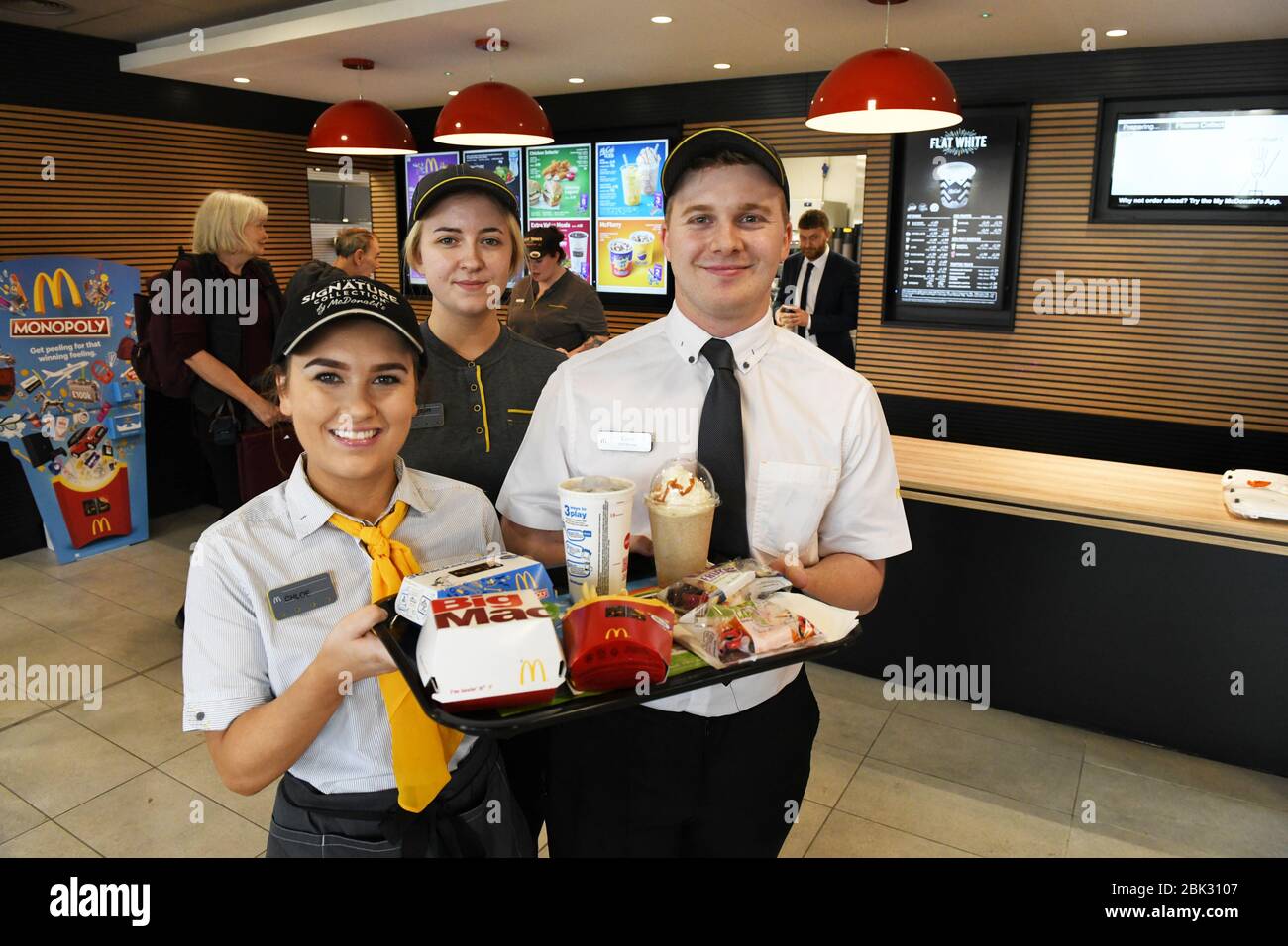 Ritratto di tre McDonalds personale ristorante in uniforme nel Regno Unito, guardando la macchina fotografica e tenendo vassoi di cibo. Foto Stock